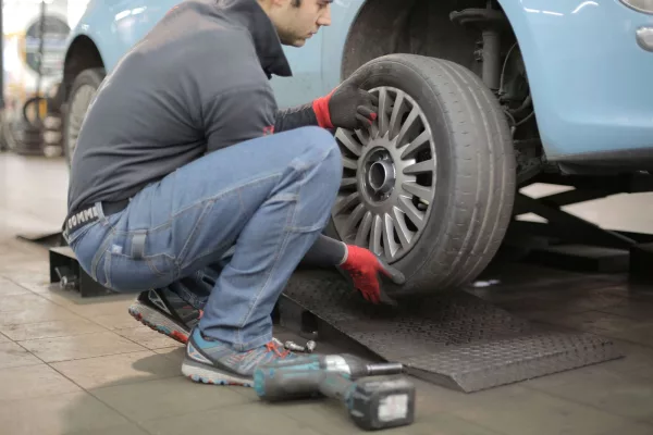 Mécanicien montant un pneu sur une voiture en atelier